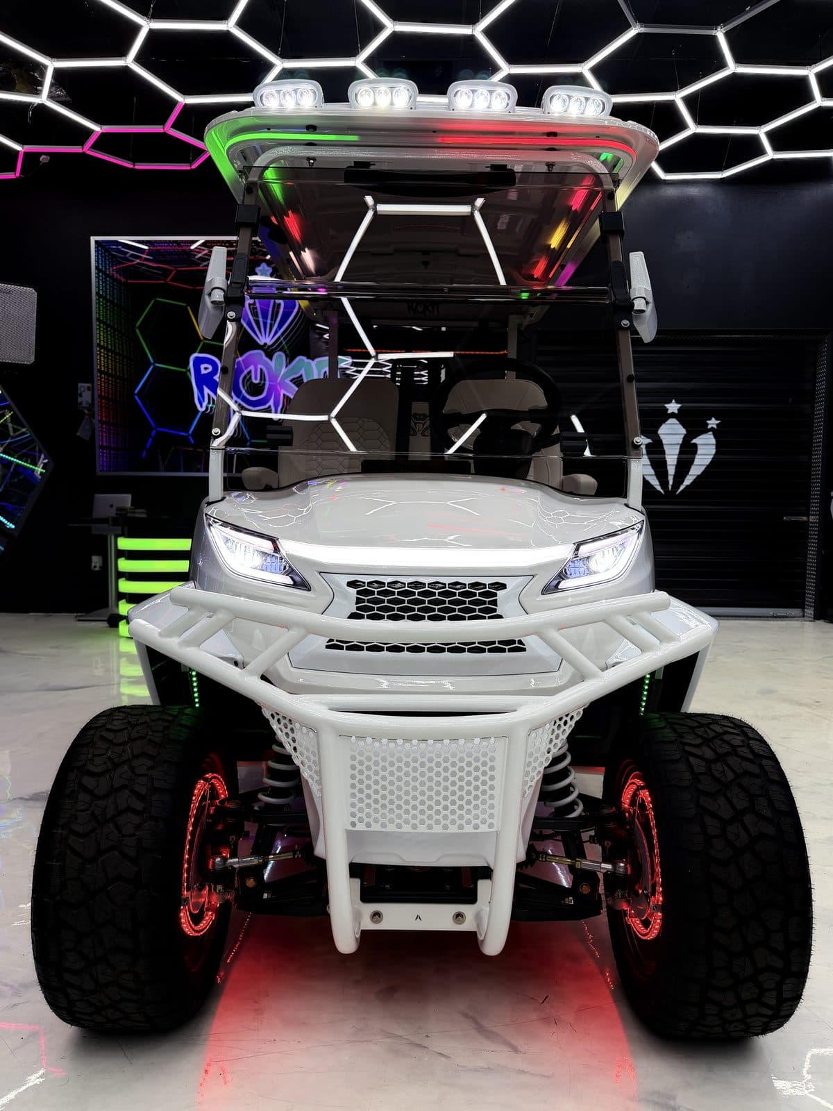 ROKIT Edition Venom EV in white, head-on, showing the LED light bar, DOT windshield and brush guard, in the ROKIT Carts showroom